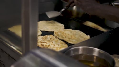 Vendor Frying Roti Frata Street Food On Griddle At Tekka Centre Market In Singapore. - close up