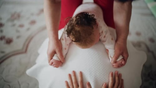 Infant Supported by Adult on Pillowed Surface Indoors