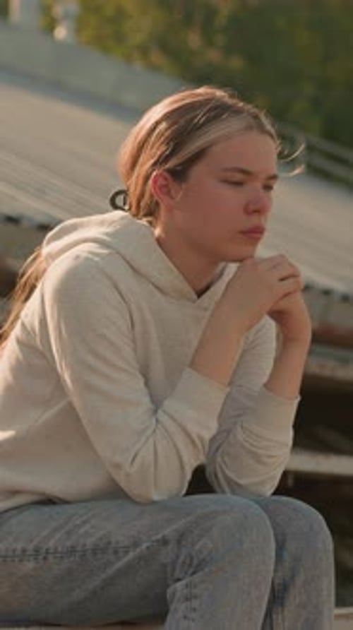 Contemplative Woman Sitting on Rustic Stadium Bleachers in Thoughtful Reflection