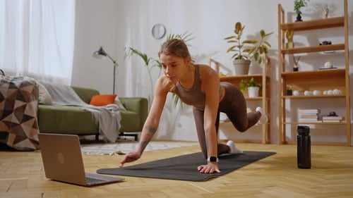 Sporty Woman Following Training Video on Laptop Indoors