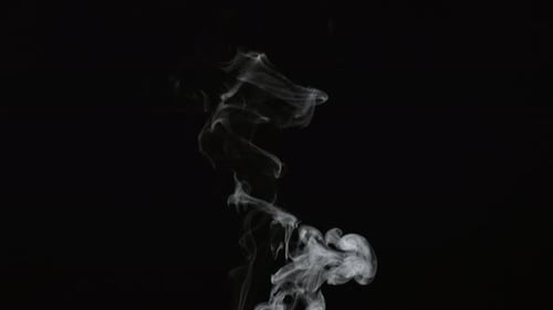 Wispy smoke slowly rising against black background