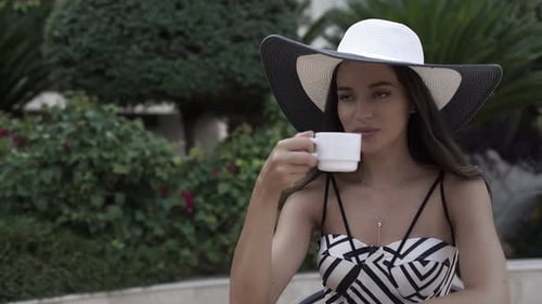 Elegant Woman Enjoying Beverage in Urban Garden