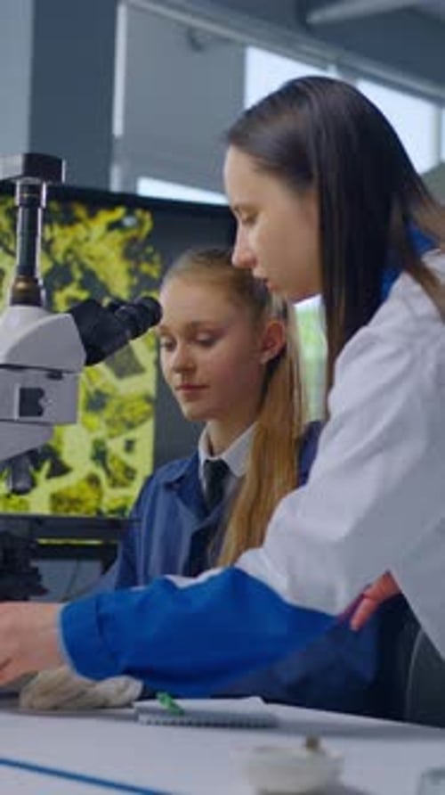 Girl Student and Teacher Using Microscope in Laboratory