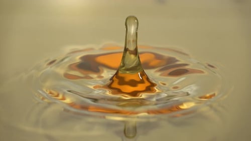 Macro Liquid Gold Water Drop Creates Splashes