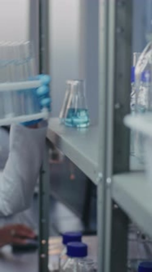 Une chimiste sort des tubes à essai d'une étagère avec de la verrerie de laboratoire