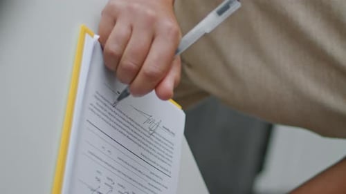 Signing a Document on Yellow Clipboard