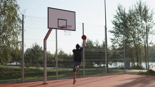Man on Street Basketball Court Dribbles Ball Throws It Into Hoop and Enjoy