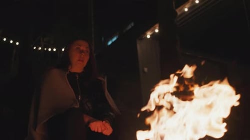 Woman Warming Hands by Bonfire at Night