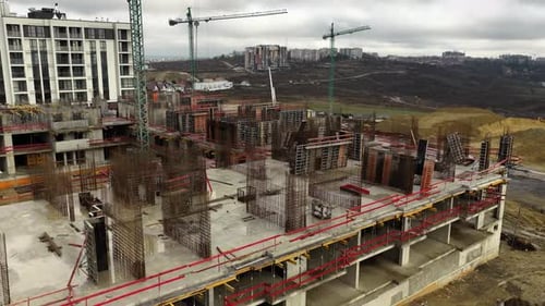 Cinematic rightward orbit around active construction site with exposed rebar columns and concrete st