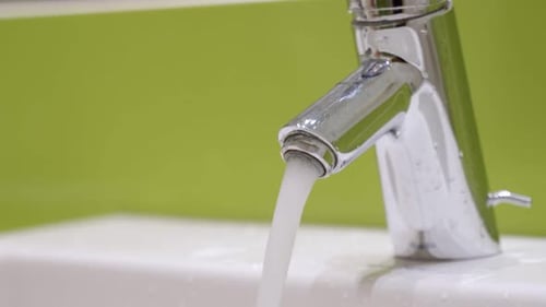 Chrome Faucet and Running Water in Bathroom Sink
