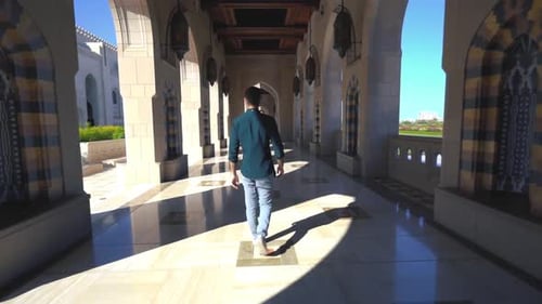 Casual man visits the Grand Mosque Muscat and strolls through the hallways - Oman.Tracking shot.