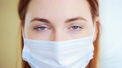 Close-up portrait of a red-haired Caucasian girl or woman with blue eyes in a protective medical