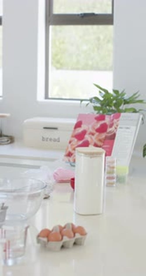 Vertical video: Camera panning across kitchen counter showing white canister eggs bowl for baking