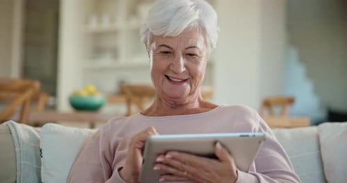 Senior Woman Laughing While Using Tablet at Home
