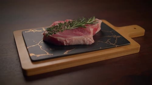 A Display of Fresh Raw Meat on a Wooden Cutting Board Complemented By Fragrant Herbs