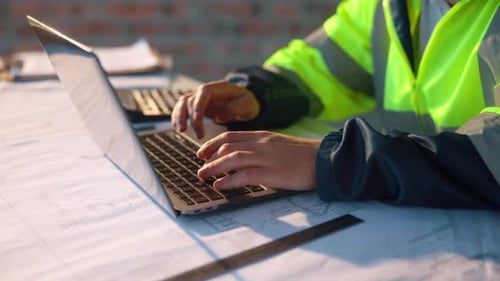 Mann, Laptop und Hände auf der Baustelle zur Planung, Materialbestellung oder Terminaktualisierung