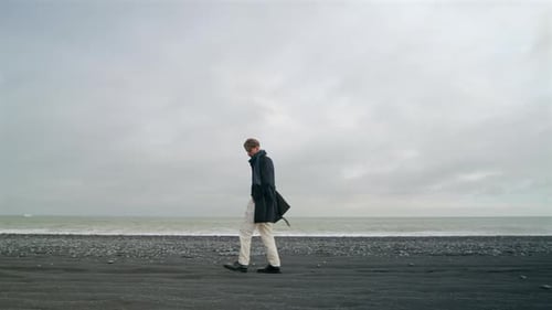 A Young Man Walking on the Stunning Reynisfjara Black Sand Beach in Beautiful Iceland