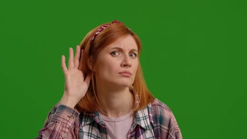 Woman, hand and ear for listening by green screen with confused face, thinking and attention