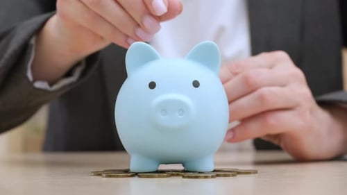 Businesswoman in Suit Putting Coins in Blue Piggy Bank Close Up Money Saving
