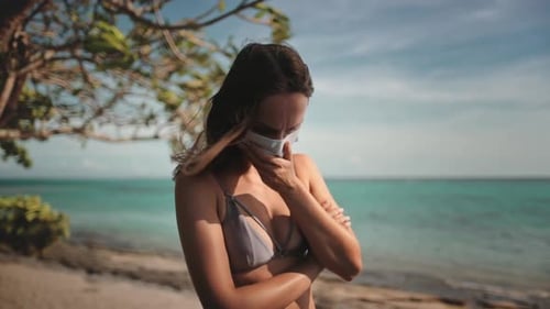 Woman with COVID19 Medical Mask on a Sunny Beach