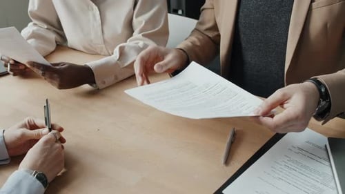 Kaukasische Bewerberin unterzeichnet Arbeitsvertrag mit zwei multiethnischen Personalvertretern