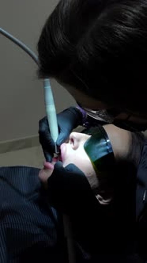 Dentist Performing Teeth Whitening Procedure on Female Patient