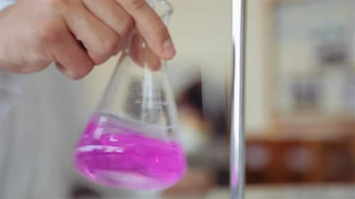 Scientifique mélangeant du titrant et de l'analyte dans une fiole Erlenmeyer (fiole conique) en agitant une orbitale