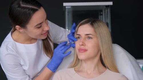 A Professional Beautician Injects Botox Into the Face of a Young Blonde
