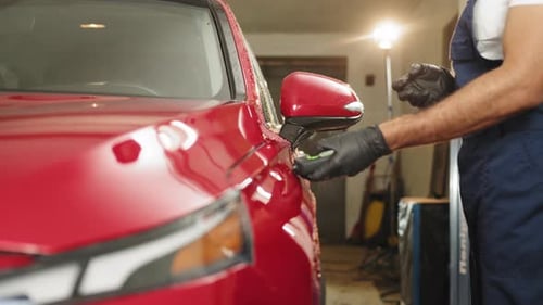 Inspecteur mesurant l'épaisseur de la couche de peinture de la carrosserie rouge sur le véhicule