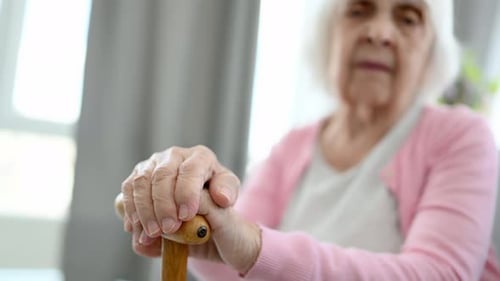 Senior Woman Resting Hands on Wooden Walking Cane