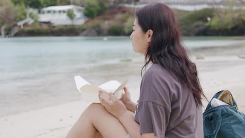 Adult Asian woman eating fast food on the beach, outdoor portrait