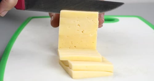 Cortando o queijo em pedaços com uma faca de perto