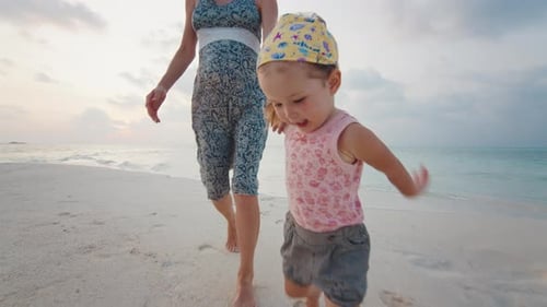Mother and daughter walk on the beach in tropics