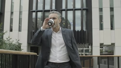 Corporate business man walking to work in city of London and drinking coffee