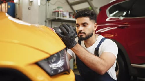 Man Polishing Car Hood in Auto Repair Shop