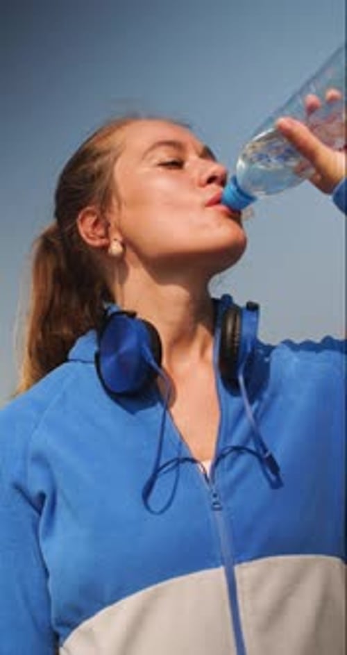 Woman Drinking Water After Exercising Outdoors