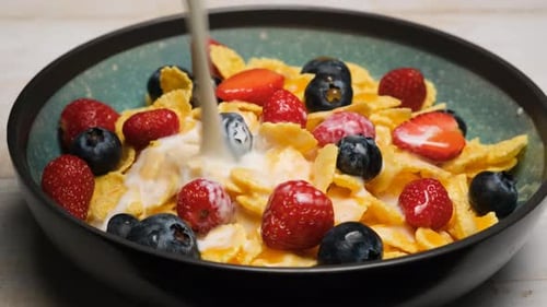 Milk Being Poured onto Breakfast Cereal with Berries