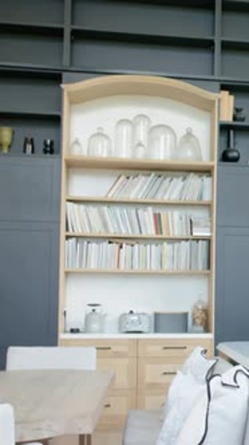 Vidéo verticale : caméra panoramique centrant une grande bibliothèque dans la salle à manger, révélant des cloches, des livres