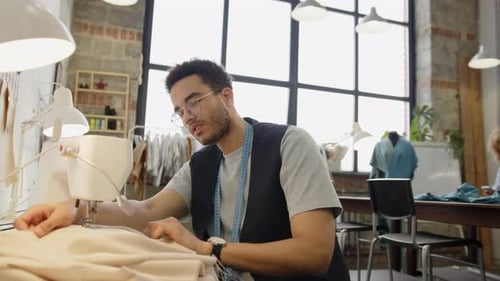Young Tailor Using Sewing Machine in Workshop