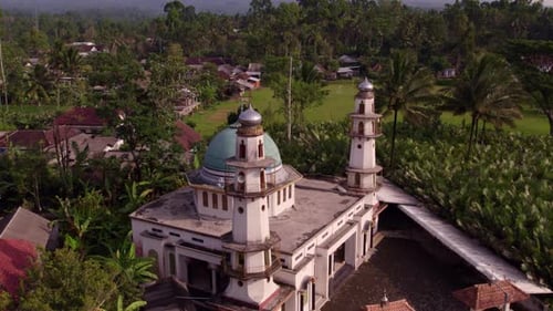 Aerial view of tropical village with mosque and volcano, Indonesia.