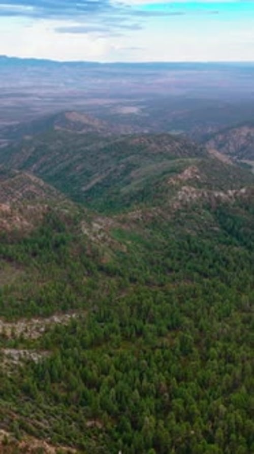 Mountainous panorama on cloudy daytime. Drone footage over the rocky landscape overgrown