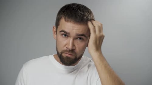 Man Touches Hair and Rubs Forehead Close Up