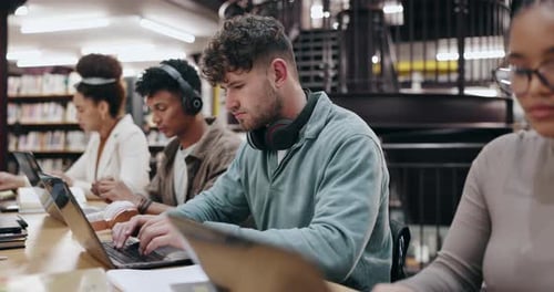 Research, typing and laptop with man in library for knowledge, education and college thesis