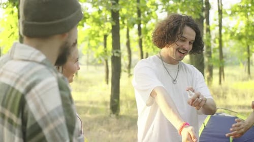 A Group of Young Tourists in a Beautiful Forest Applying Mosquito Repellent at Sunset Against the