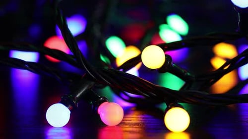 Bright Christmas lights glowing on table in darkness, closeup