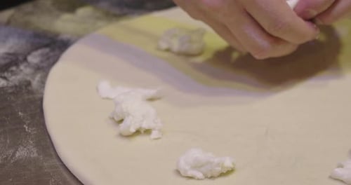 Close up of a pizza chef's hands kneading the dough to prepare a gourmet pizza and spreads the tom