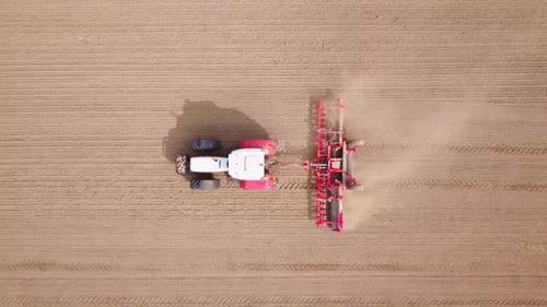 Tracteur rouge labourant la terre ferme - Images aériennes