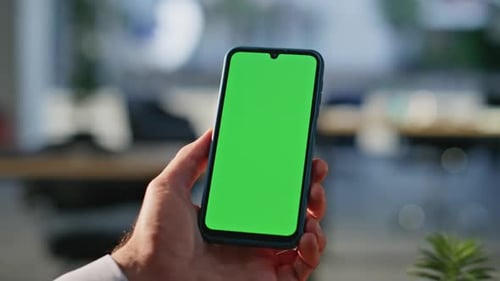 Man Hand Holding Green Screen Mobile Phone Having Video Call in Office Closeup