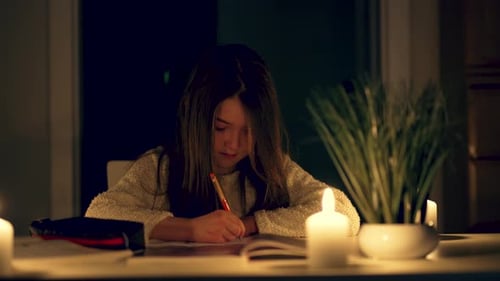 Girl Writing By Candlelight in Dark Home Interior