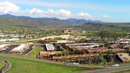 A drone captures a busy highway and industrial park while picturesque mountains sit on the horizon.